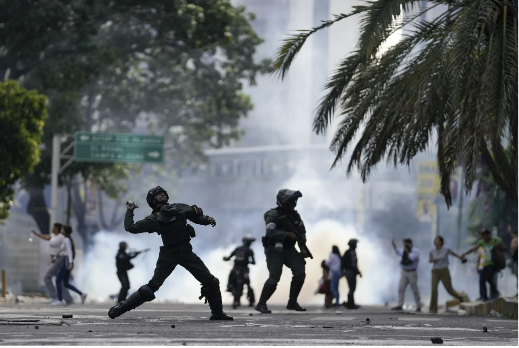 Cтолкновения между полицией и протестующими в Венесуэле. Полицейский бросает газовый баллончик в протестующих