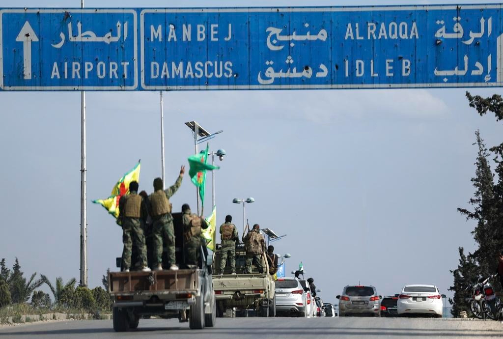 Курдские бойцы стоят на своих машинах во время вывода войск из двух районов Алеппо в рамках соглашения с сирийским центральным правительством